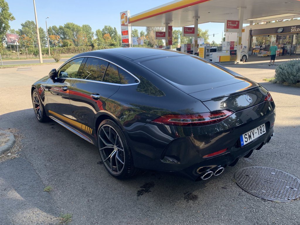 Frissen mosott fekete Mercedes-AMG GT hátsó háromnegyedes nézetből, csillogó karosszériával